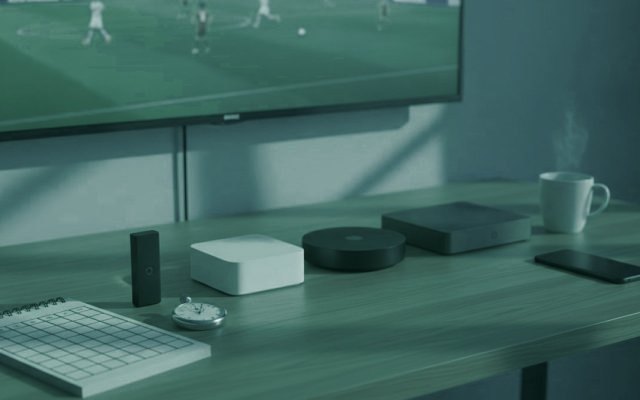Five streaming devices, a notebook scoring grid and a stopwatch in front of a TV showing a football match