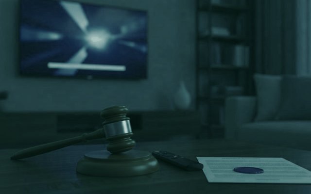 A judge gavel, a streaming remote and a sealed document on a coffee table in front of a TV